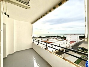 A balcony with a view of a coastal cityscape, including buildings and a body of water.