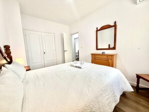 Ein Hotelzimmer mit einem Bett, einem Holzschrank, einem Spiegel und einer Tür.