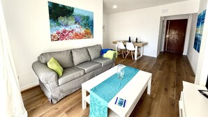 Una sala de estar con un sofá gris, una mesa de centro blanca y un cuadro en la pared.