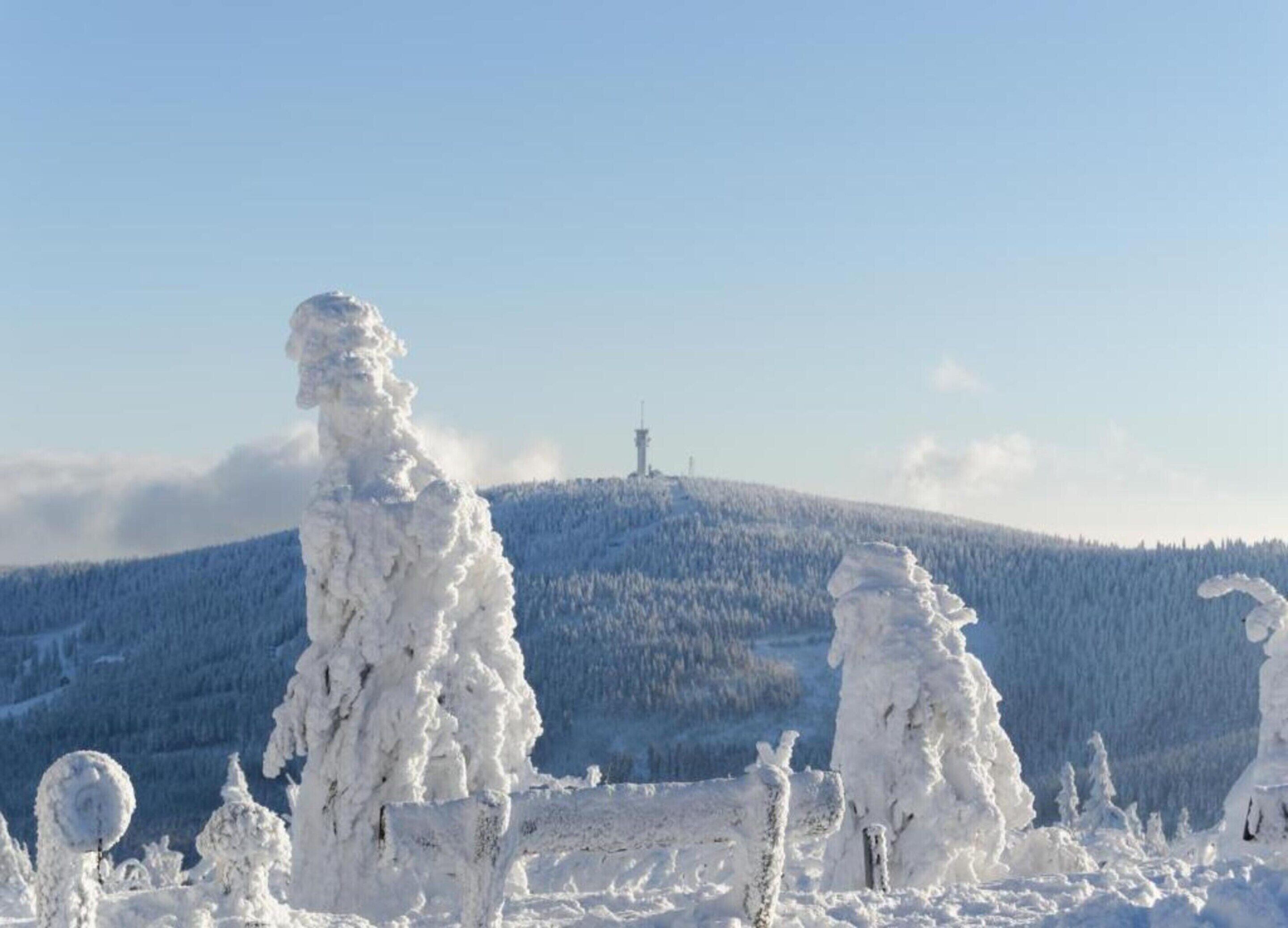 A snow-covered landscape with a prominent hill and a tower in the distance.