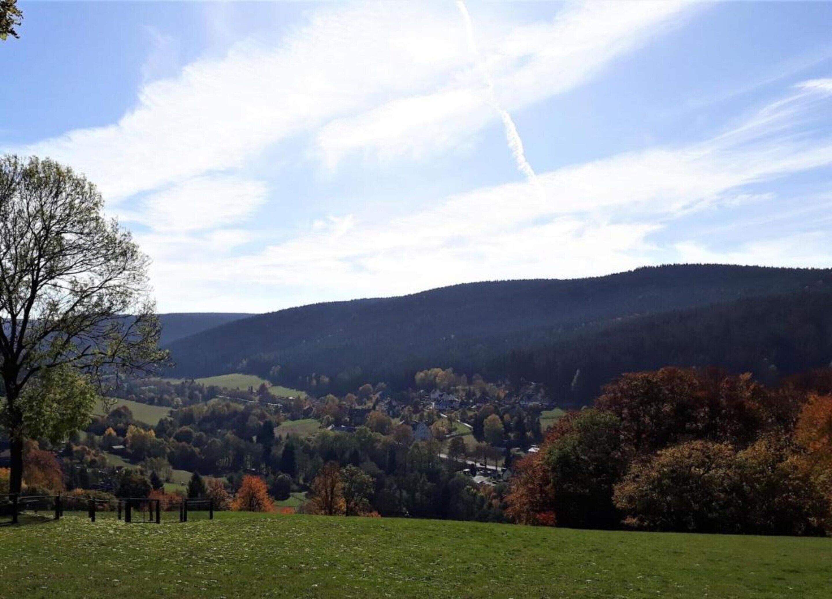 Paisagem rural com colinas ondulantes, uma pequena aldeia e céu claro.