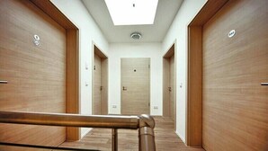 Un pasillo con puertas de madera, tragaluces y una barandilla de metal.