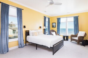 A hotel room with a bed, a chair, a small table, and a view of the ocean. - Spacious 7-bedroom oceanfront home on Folly Beach with breathtaking views, large (Folly Beach)