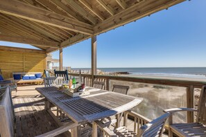 A wooden deck with a table and chairs, overlooking a beach. - Spacious 7-bedroom oceanfront home on Folly Beach with breathtaking views, large (Folly Beach)