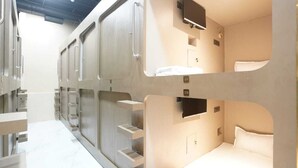A modern hotel room with bunk beds, a television, and a small bathroom. - ASTROPOD (Mumbai)