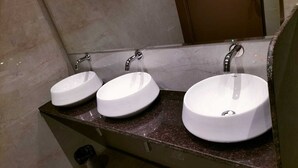 A bathroom with three white sinks, each with a single faucet, and a mirror above them. - ASTROPOD (Mumbai)