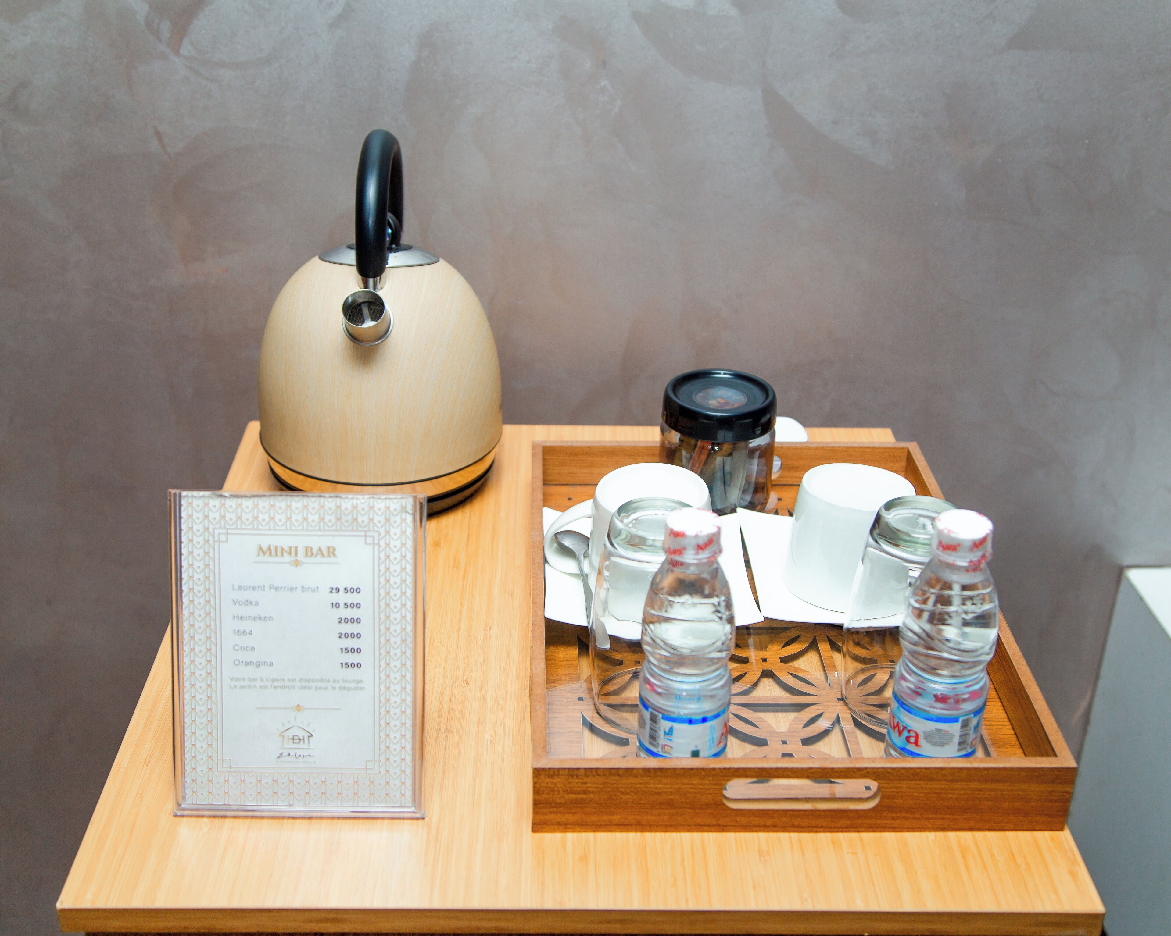 A wooden tray with a teapot, cups, and bottles of water, along with a menu on a table.