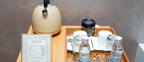 A wooden tray with a teapot, cups, and bottles of water, along with a menu on a table.