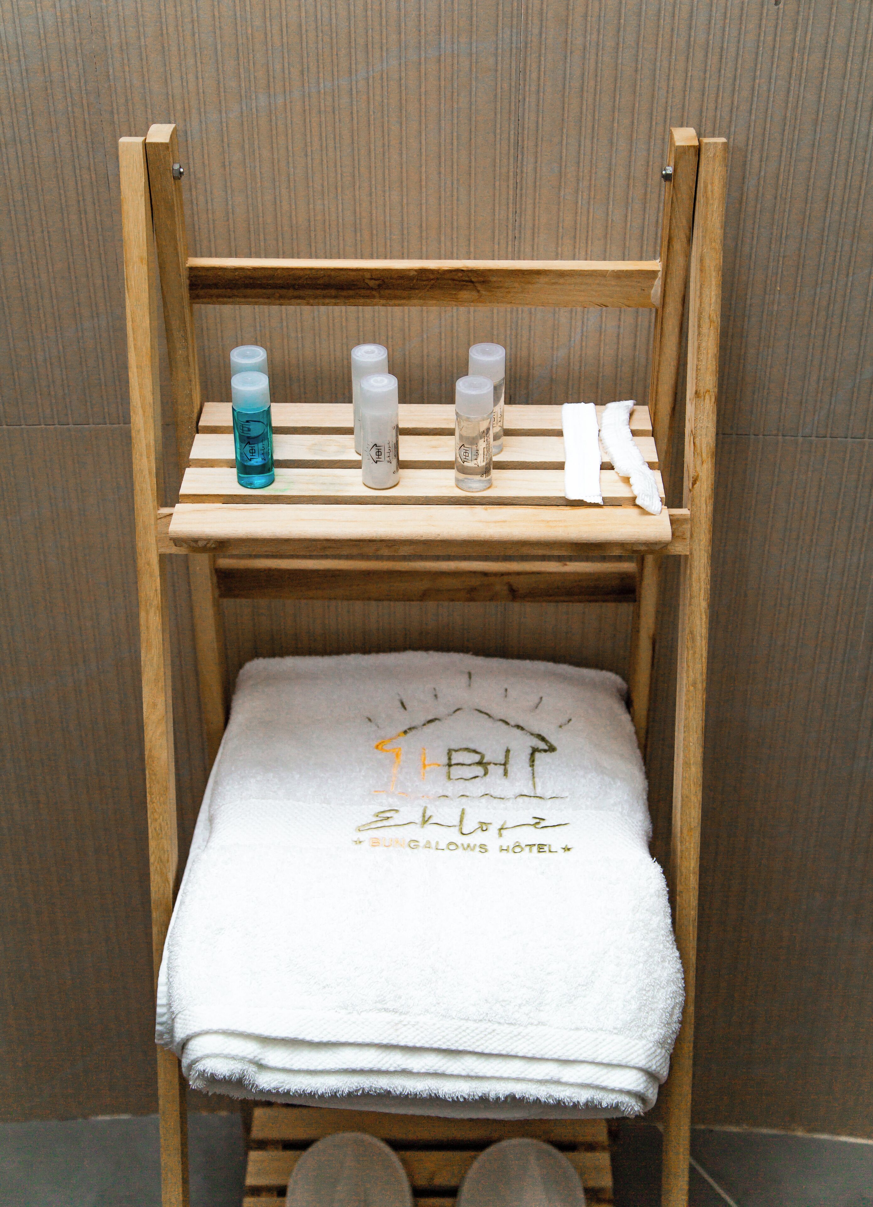 A wooden bench with a towel and three bottles on it.