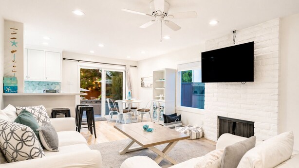 A modern living room with a fireplace, a flat-screen TV, and a dining area with outdoor visibility. - Perfect 4 Families, Walk 2 Beach, Private Hot Tub* (Ventura)