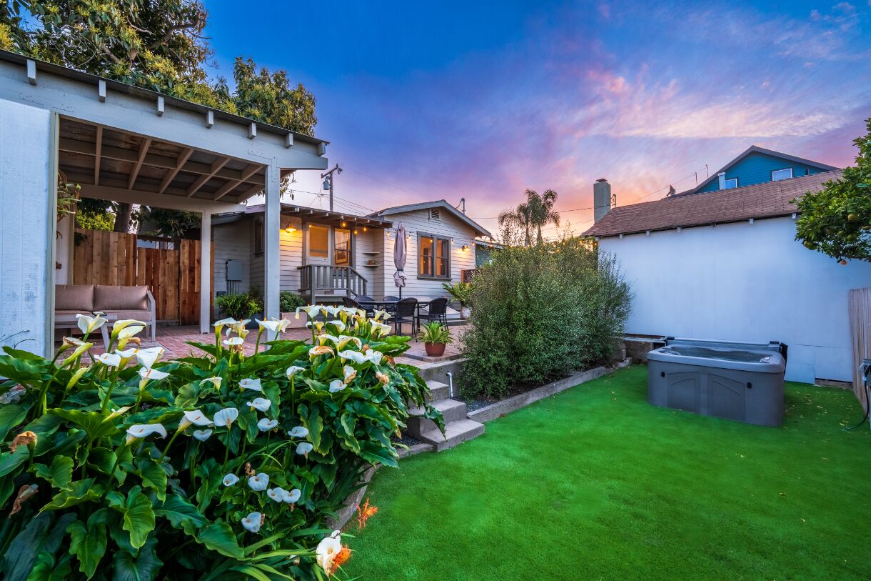 A backyard with a patio, outdoor furniture, a hot tub, and a well-maintained lawn.