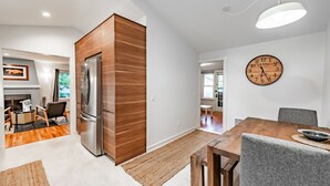Une cuisine moderne dotée d’un r éfrigérateur encastré, de meubles en bois et d’un coin repas avec une table et des chaises en bois.