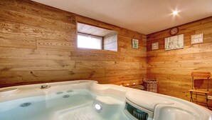 L’intérieur d’un chalet en bois, avec un jacuzzi, une petite fenêtre et des murs en bois.