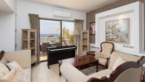 Un salon avec un piano, des canapés, une table et une grande fenêtre donnant sur un beau paysage.