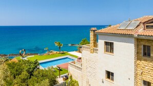 Une propriété située sur la côte, dotée d’une piscine, d’une construction en pierre et offrant une vue sur l’océan.