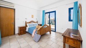 A bedroom with a wooden bed, a nightstand, a desk, and a window with curtains. - Villa Ermis in Peyia (Pegeia)