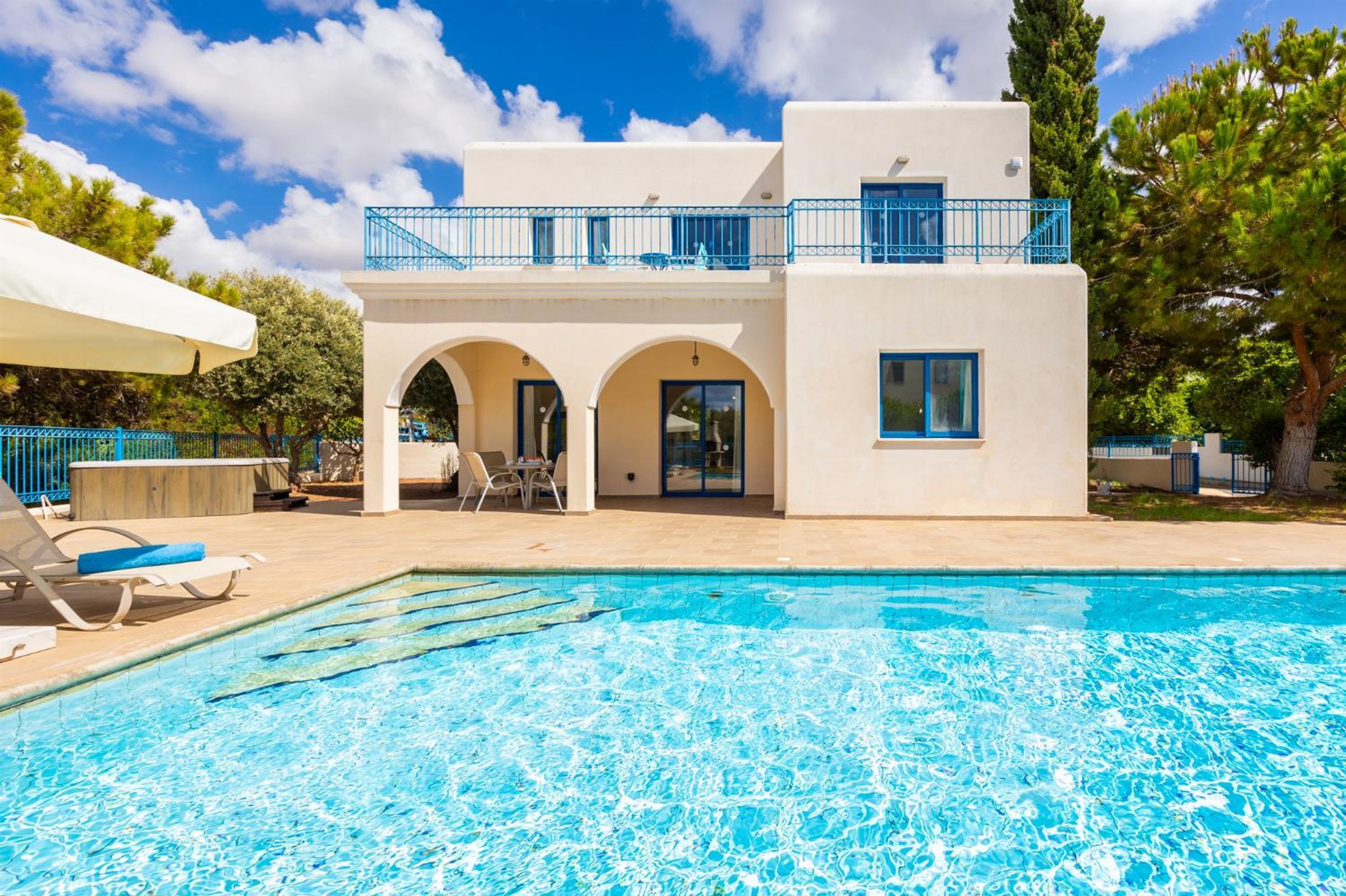 A modern building with a swimming pool, a covered patio, and a blue railing.