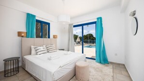Un dormitorio moderno con una cama grande, una mesita de noche pequeña y vista a una piscina a través de un ventanal.