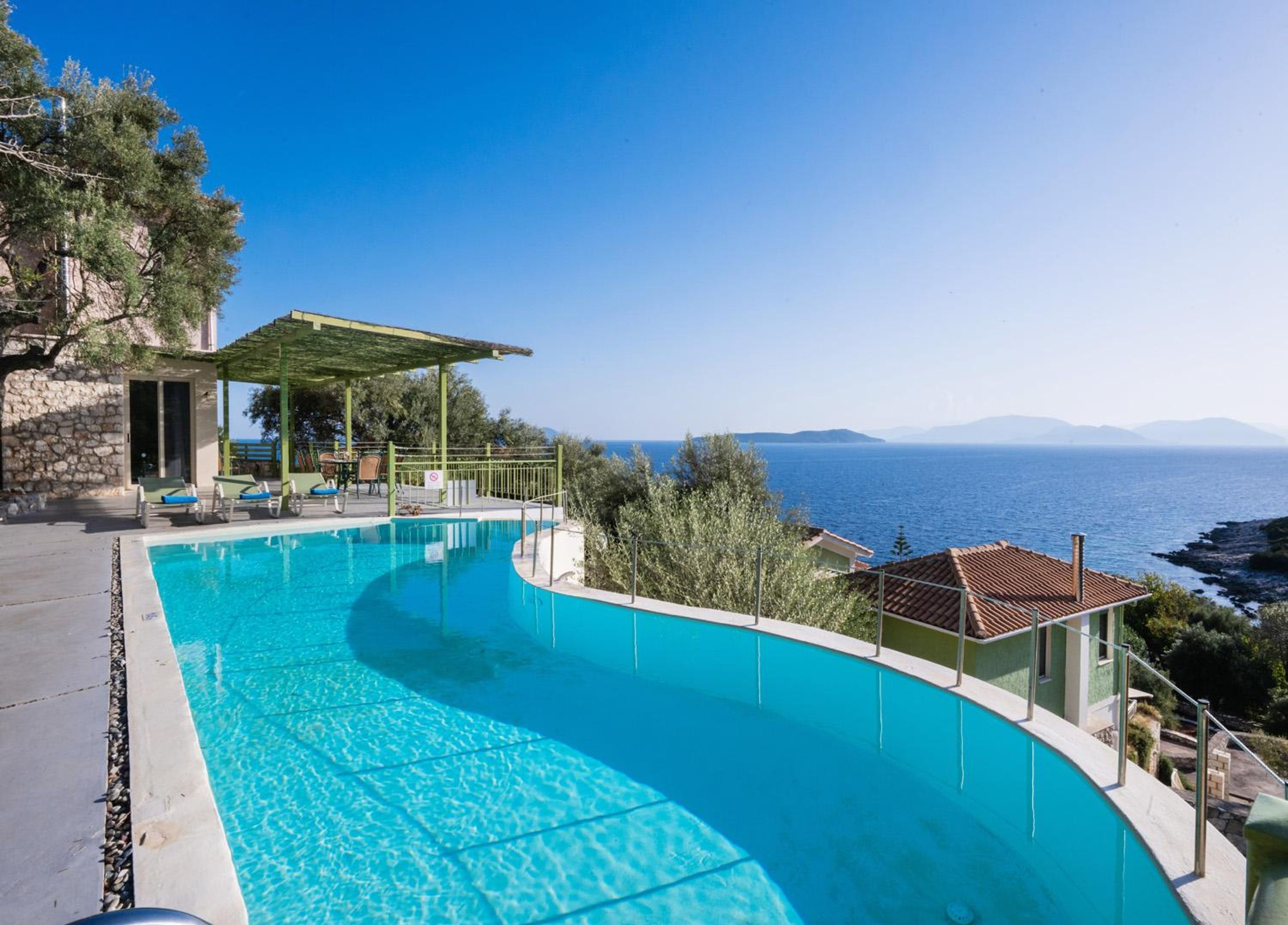 Une piscine à débordement aux formes arrondies, offrant une vue sur la mer et les montagnes.