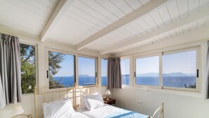 Une chambre à coucher avec un lit, une table de chevet et une fenêtre donnant sur la mer et les montagnes.