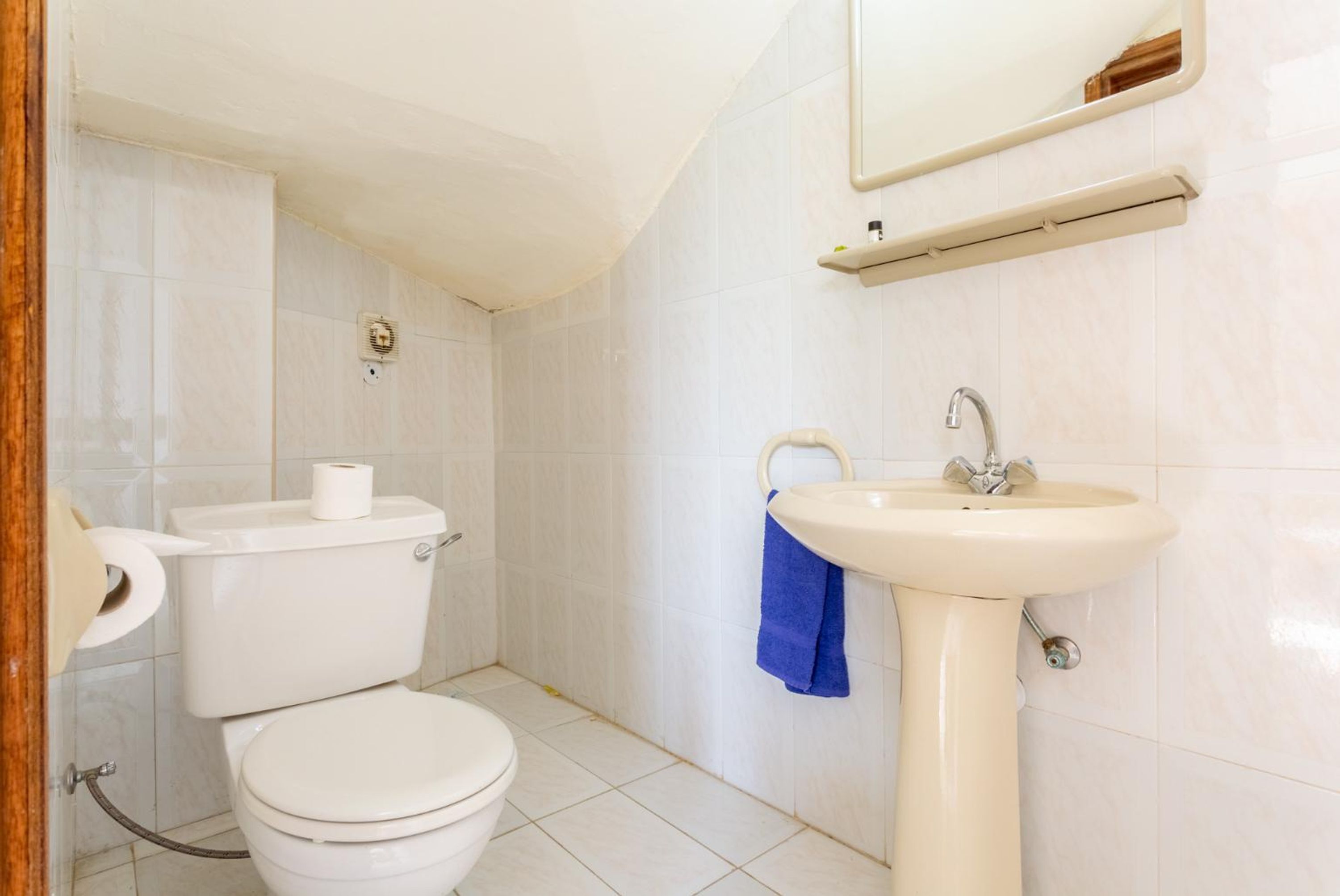 A bathroom with a toilet, sink, and mirror.