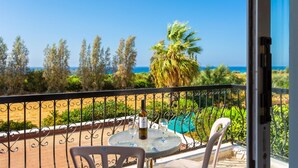 Ein Balkon mit Tisch, zwei Stühlen und einer Weinflasche.