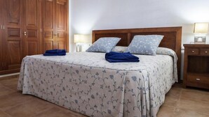 A bedroom with a large bed, wooden wardrobe, bedside lamps, and a nightstand. - Casa Morro Blanco in Conil (Tías)