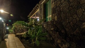 A stone-walled building with a tiled pathway and green shutters. - Casa Morro Blanco in Conil (Tías)