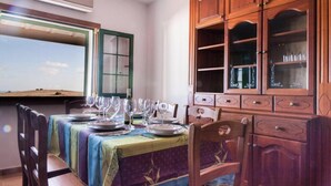 A dining area with a table set for four, a wooden cabinet with glass doors, and a window with a view of the sky. - Casa Morro Blanco in Conil (Tías)