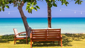 A wooden bench and chair under a tree by a clear blue sea. - Villa Christos in Argaka (Argaka)
