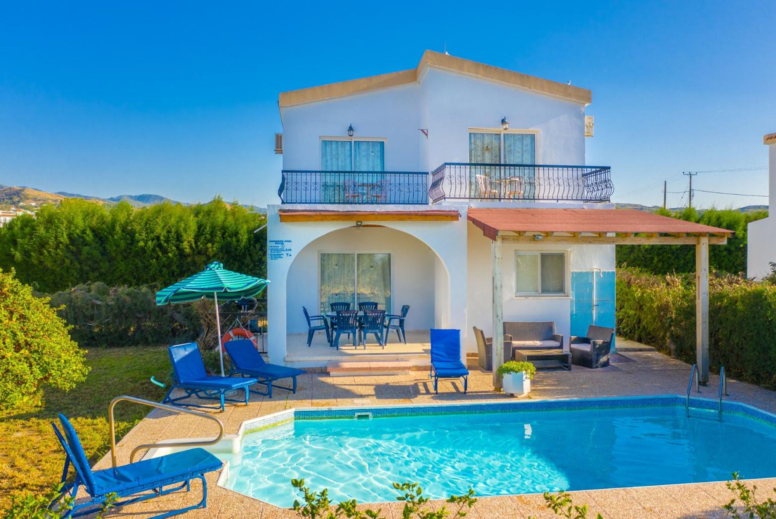 A two-story building with a swimming pool, outdoor seating, and a covered patio area.