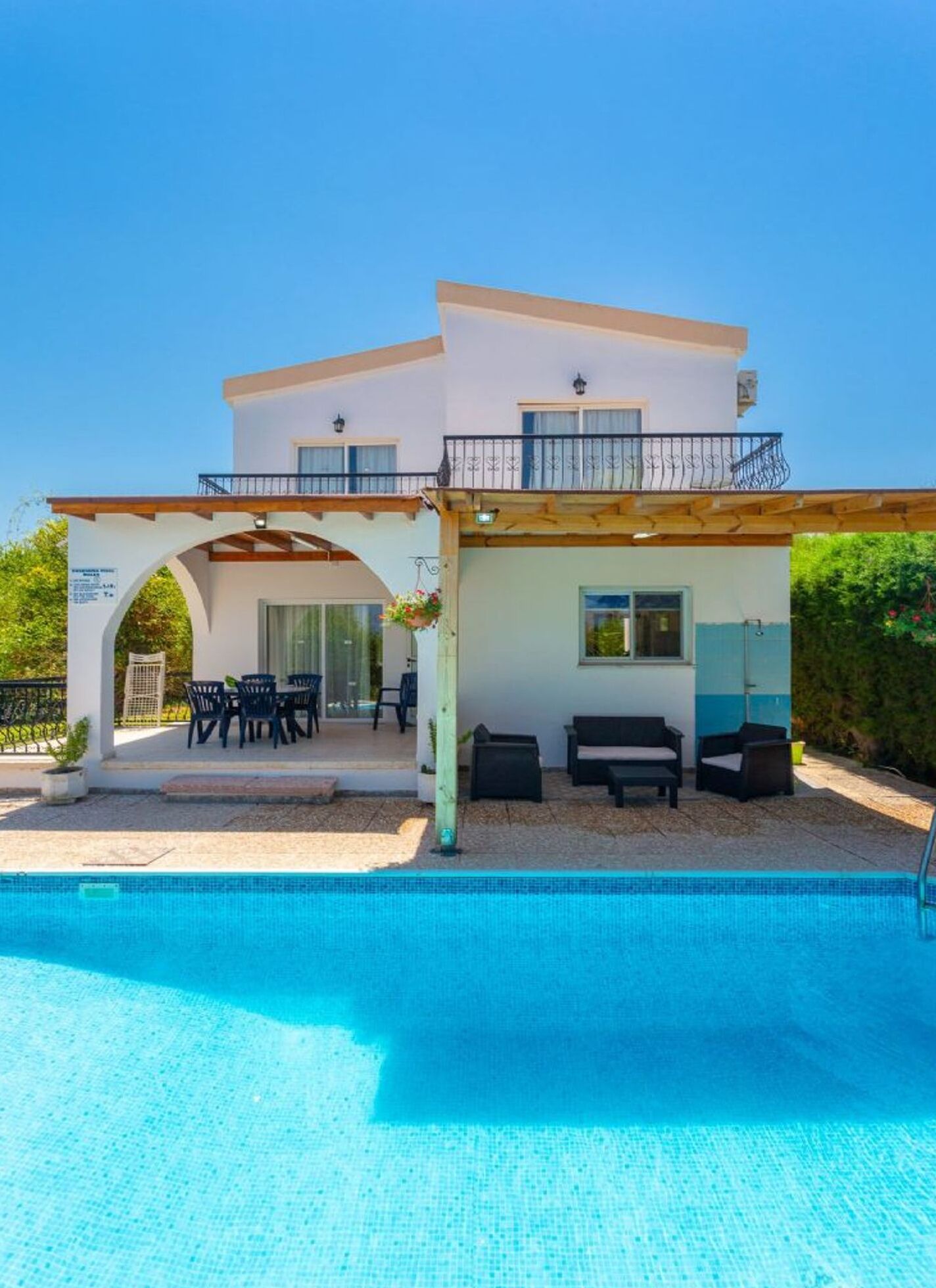 A two-story building with a covered patio area, a pool, and outdoor seating.