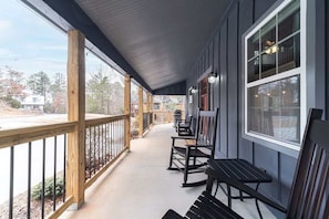 A covered porch with wooden railings, a bench, and a table.