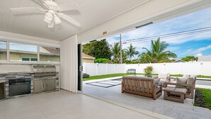 A spacious patio with a grill, outdoor furniture, and a view of the neighborhood. - Luxury Beach Home Salt Water Pool Kid Pet Friendly (Boca Raton)