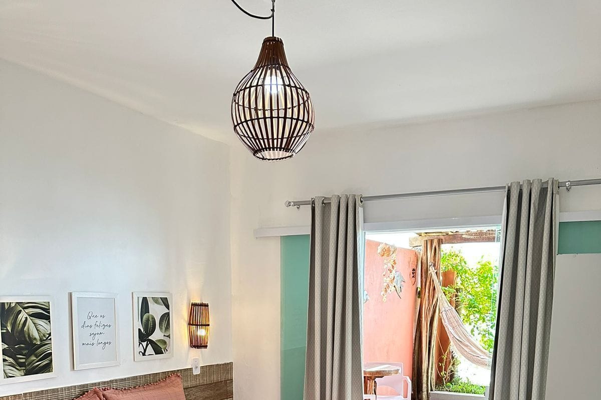 A bedroom with a bed, a hanging light fixture, and a view of the outside.