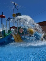 Un área de juegos acuáticos con un tobogán y múltiples chorros de agua.