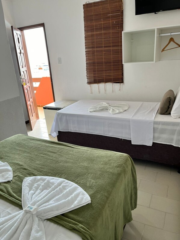 A hotel room with two beds, a TV mounted on the wall, and a window with blinds. - Pousada Mar da Gamboa (Cairu)