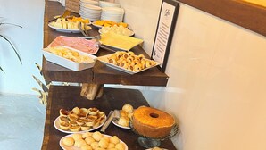 Ein reichhaltiges Buffet mit verschiedenen Speisen, darunter Gebäck, Brot und Kuchen.