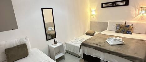 A hotel room with two beds, a bedside table, a mirror, and a hanging light fixture.