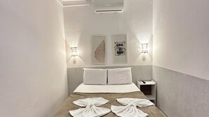 Ein modernes Hotelzimmer mit Bett, Klimaanlage, Wandleuchten und Kunstwerken.