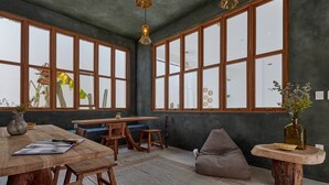A spacious room with large windows, wooden furniture, and hanging pendant lights. - CASA OHMA, an elegant Maison de Charme with swimming pool in La Punta (Punta de Zicatela)