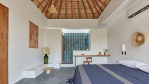 A bedroom with a bed, a desk, a chair, a lamp, and a small table. - CASA OHMA, an elegant Maison de Charme with swimming pool in La Punta (Punta de Zicatela)