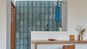 A modern kitchen with a wooden chair, a striped backsplash, and a blue hanging light fixture. - CASA OHMA, an elegant Maison de Charme with swimming pool in La Punta (Punta de Zicatela)