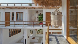A multi-level white building with wooden balconies, large windows, and a hanging woven light fixture. - CASA OHMA, an elegant Maison de Charme with swimming pool in La Punta (Punta de Zicatela)