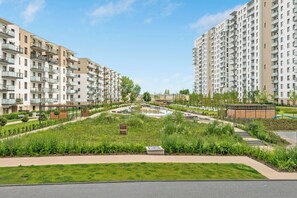 A residential complex with multiple apartment buildings, a central landscaped area with pathways, and a small pond.