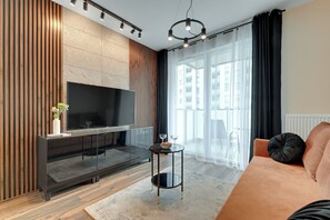 A modern living room with a flat-screen TV, a glass coffee table, and a sofa. - Seaside Gdańsk Letnica by Downtown Apartments (Gdansk)
