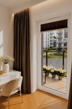 A room with a white desk, a chair, a window with a view of a balcony, and a curtain. - Seaside Gdańsk Letnica by Downtown Apartments (Gdansk)