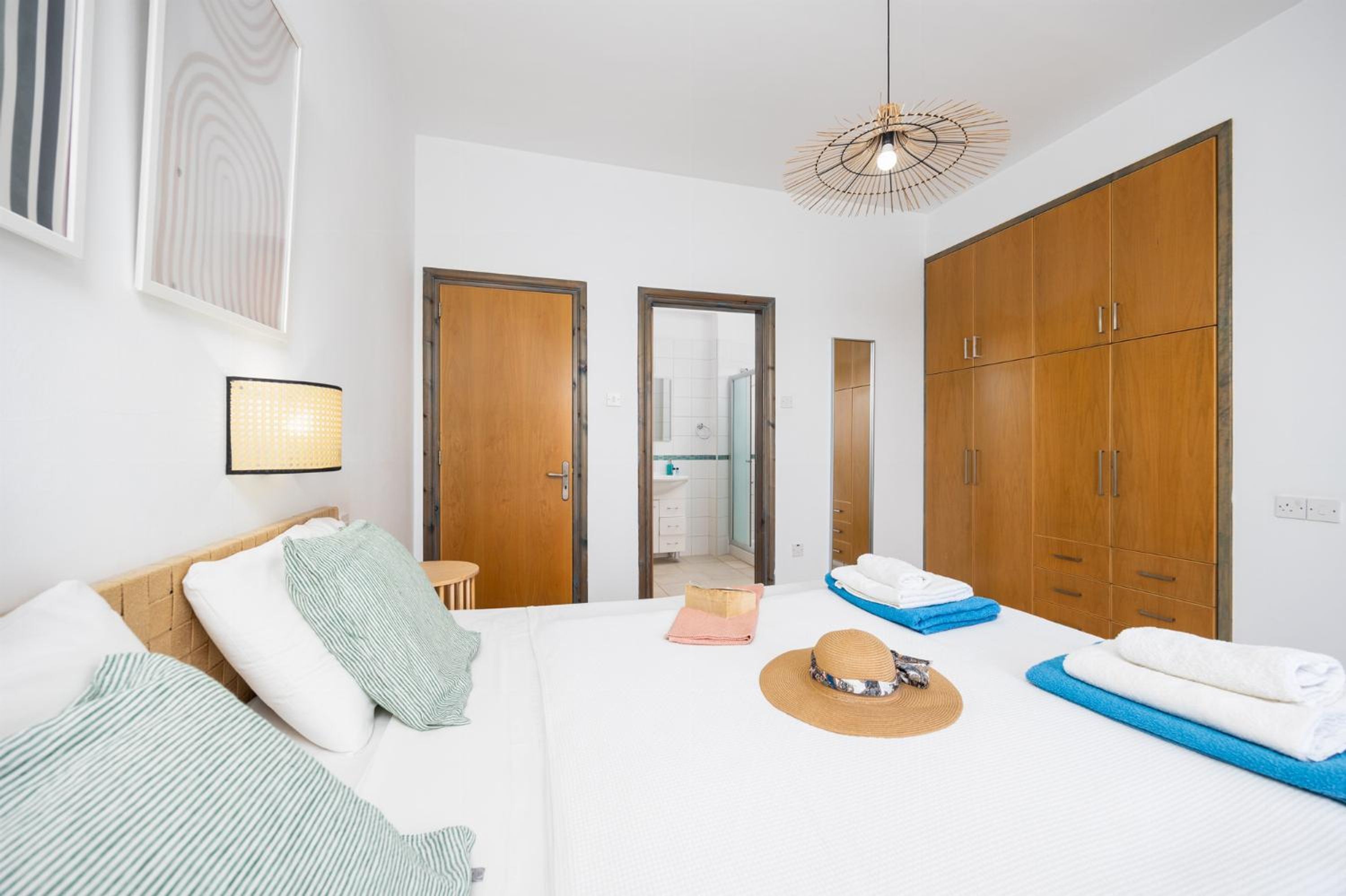 A modern hotel room with a large bed, wooden wardrobe, and a bathroom visible through an open door.