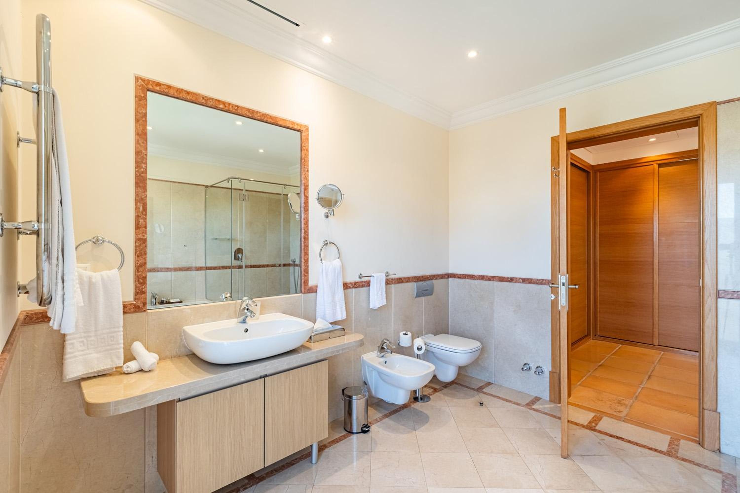 Une salle de bain moderne avec un grand miroir, un lavabo, un bidet et des toilettes.