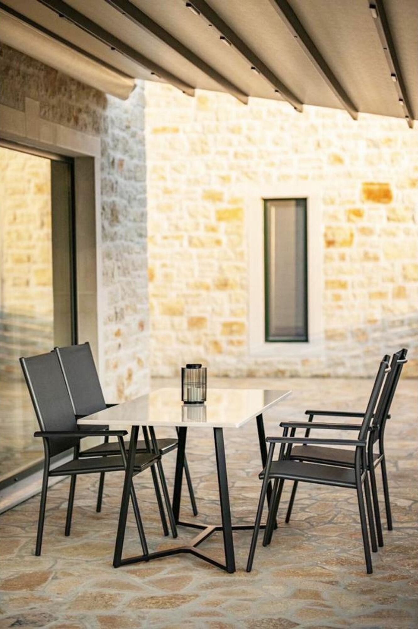 A stone-walled outdoor dining area with a table and four chairs.